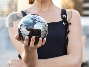 Black solar power rotating world globe held by hand